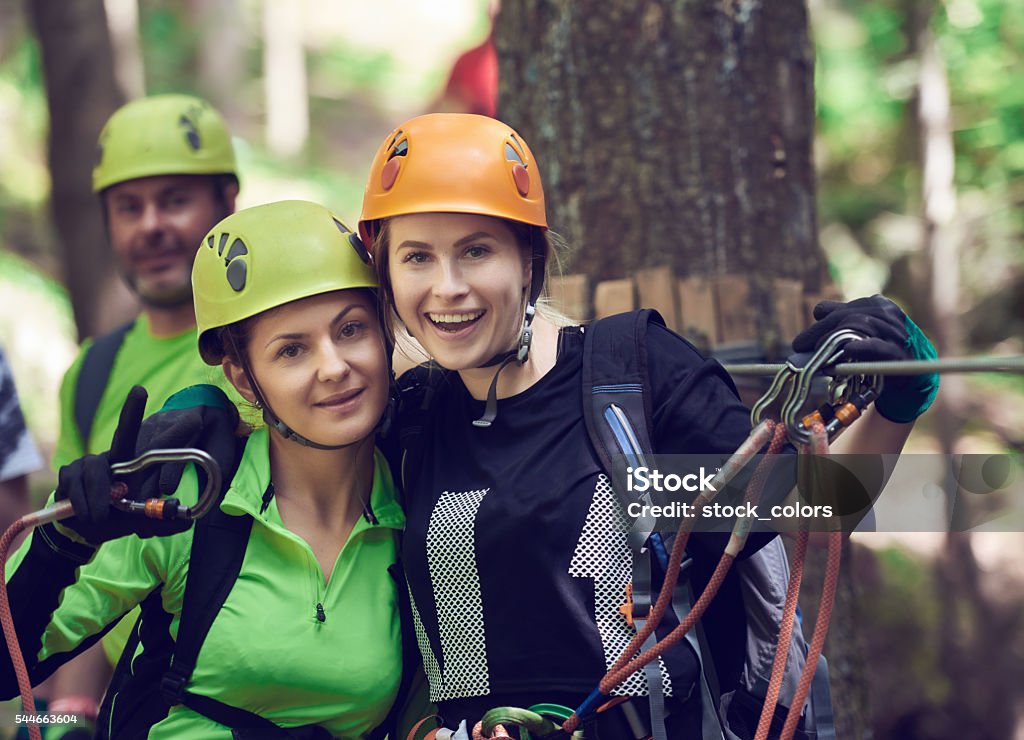 adventure friends ready for tyrolean traverse smiling friends getting ready and being equiped for a new adventure on tyrolean traverse. Zip Line Stock Photo
