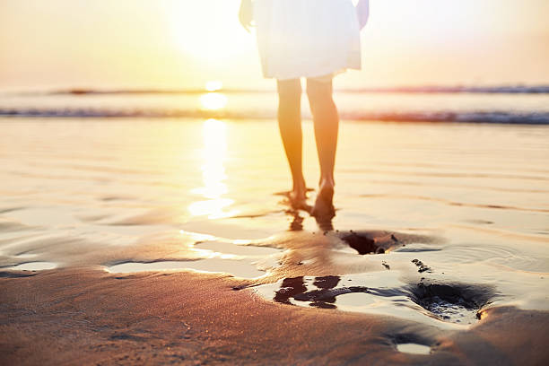 istock Low section of woman walking on wet sand during sunset 544664014