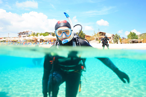 Scuba diving. Beautiful sea. Scene with  scuba divers into the sea, preparing to dive,  enjoy  in  turquoise, blue lagoon, shallow water. Over, under sea, split shot, half-half underwater turquoise lagoon.