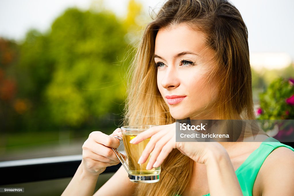 Young Woman Drinking Green Tea Outdoors Dreaming Young Woman Drinking Green Tea Outdoors. Summer Green Nature Background. Shallow Depth of Field. Dieting Stock Photo