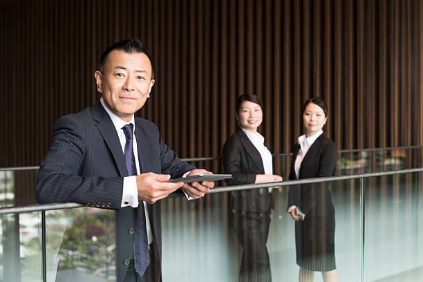 istock Mature Japanese businessman by railing holding tablet 544670214