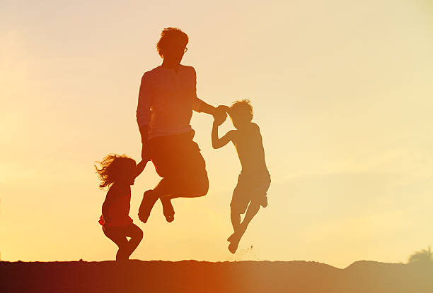istock happy father with son and daughter jumping at sunset 544670250