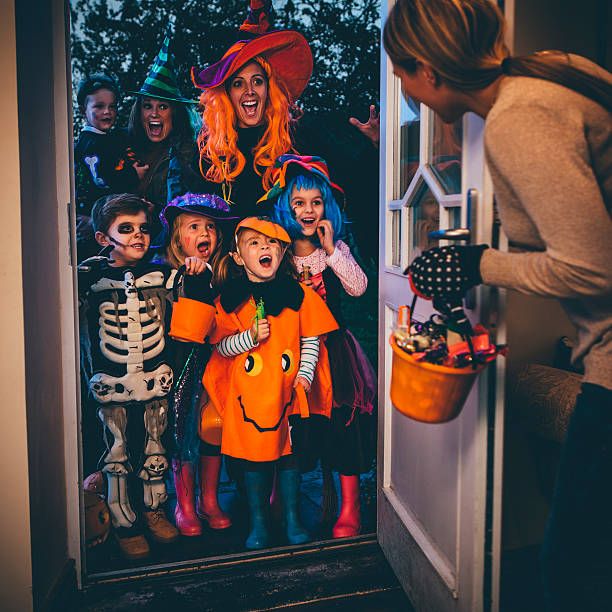 Trick or Treat! Group of children and their parents playing trick or treat on Halloween. trick or treat photos stock pictures, royalty-free photos & images