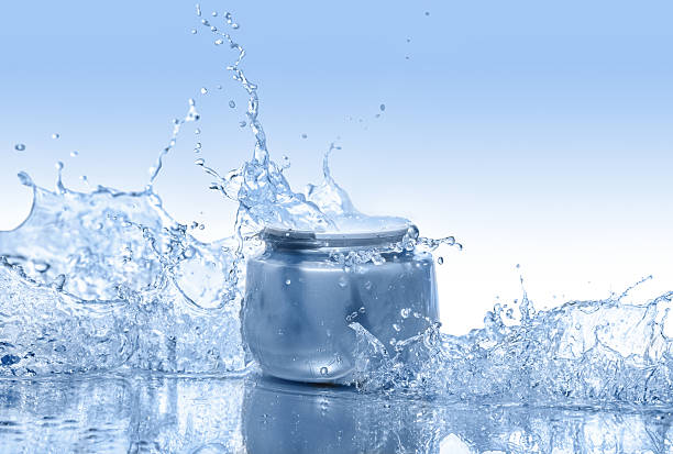 the blue jar of moisturizing cream in the big water splashes - moisten imagens e fotografias de stock