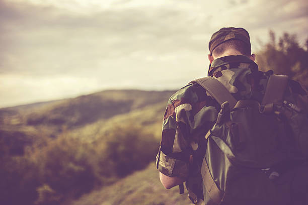 War, army and people concept - young soldier or ranger wearing military uniform in forest