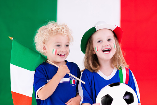 Children cheering and supporting Italian national football team. Kids fans and supporters of Italy during soccer championship.