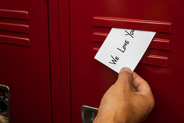 Hand Placing Anonymous Note in High School Locker stock photo