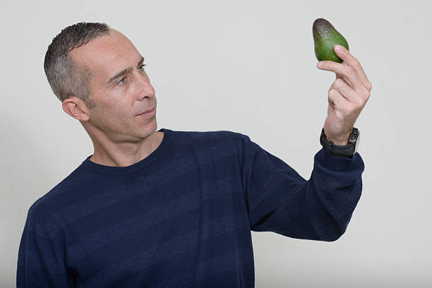 istock Studio portrait of man holding avocado 544680878