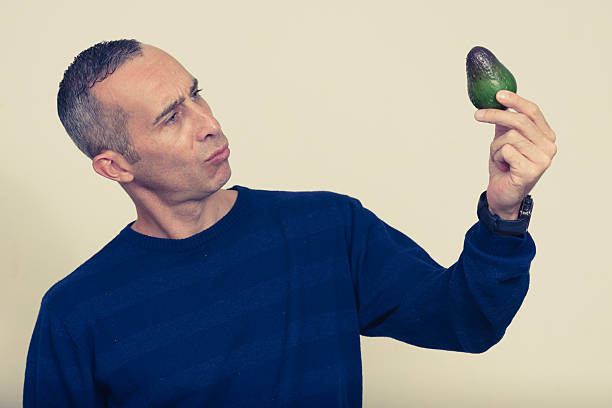 istock Studio portrait of man holding avocado 544680996
