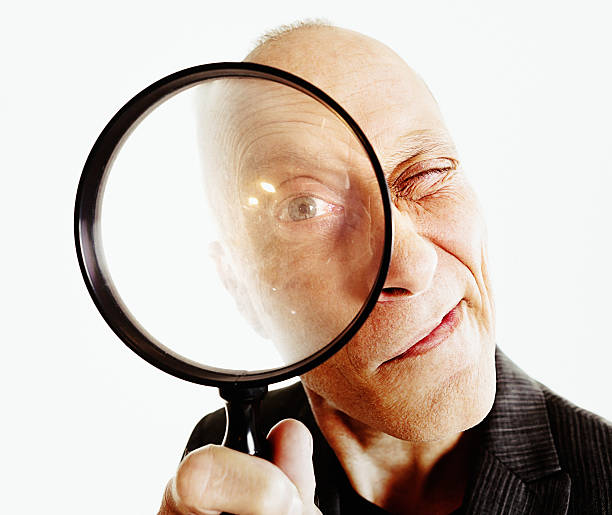istock Senior man peering curiously through magnifying glass 544684046