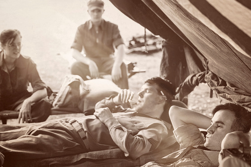 A WWII Military Unit and one worried Naval officer at rest.  Talking, eating, worrying and resting.  Copy Space.