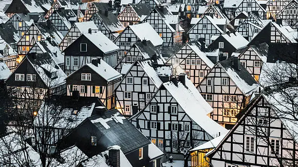Wonderful scene of a winter village in germany with snow covered roofs at the early evening. Old town with half timbered historical houses. Freudenberg old town with snow on the roofs.