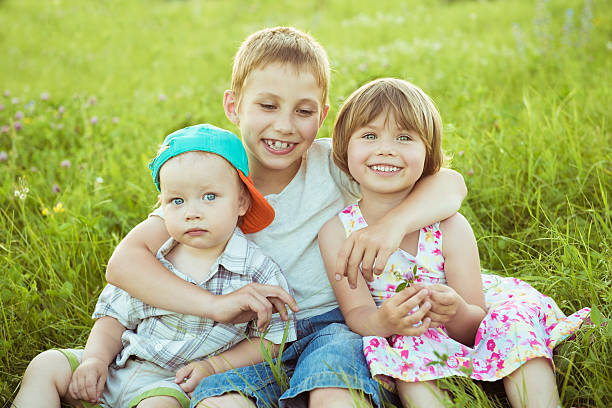 istock Three happy children sitting on meadow 544686596