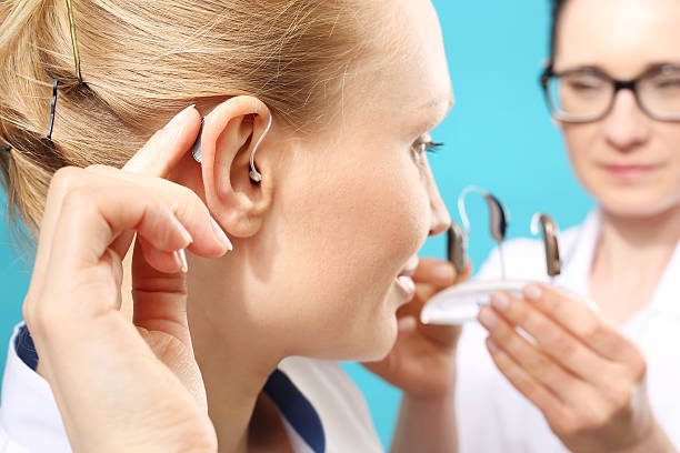 Young woman assumes a hearing aid Young woman assumes a hearing aid ear photos stock pictures, royalty-free photos & images