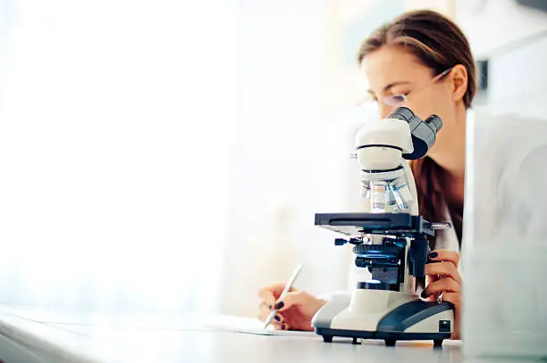 Woman using a microscope in her office