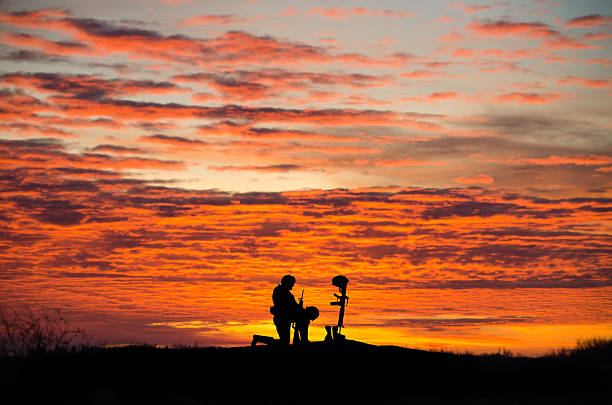 istock Soldier kneeling in front of a grave- sunset, copy space 544721548