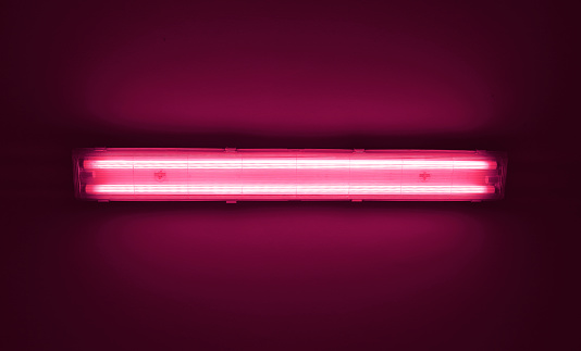 Detail shot of a fluorescent purple light tube on a wall with copyspace.