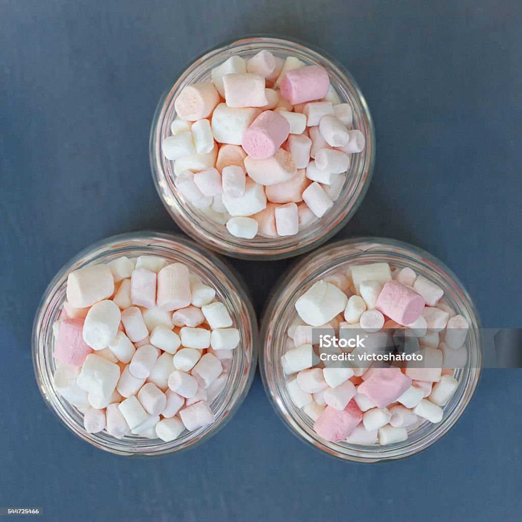 Three glass jars filled to brim marshmallow Three glass jars filled to the brim marshmallow.The view from the top. Blue Stock Photo