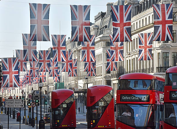 London buses London, UK - June 19th 2016:London red buses and taxi cabs under British Flag bunting along Regent street - a major retail area empty in the early morning boris bus stock pictures, royalty-free photos & images