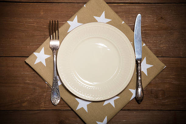 istock Plate, fork and knife on napkin on wooden background. Toned 544728654