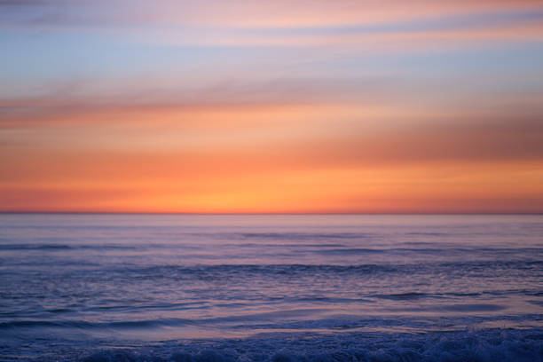 Abstract warm toned horizontal photo of sunset over ocean and waves near beach. Actual tilt/shift lens used to exaggerate blur.