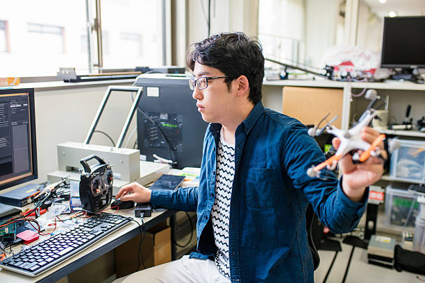 Student working on his drone design University student working on his self piloting drone design. Kyoto, Japan. May 2016 nerd stock pictures, royalty-free photos & images