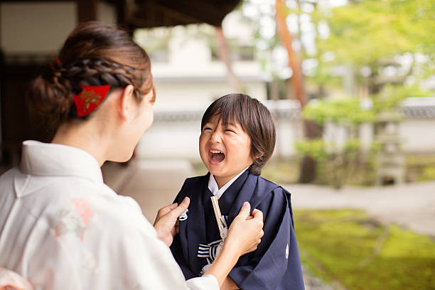Japanese Boy Laughing with Mother at the Temple Celebrating Shichigosan A young Japanese boy and his mother are wearing traditional kimono dress while celebrating shichigosan. He is smiling up at his mother while she straightens his robe. Shichigosan is a coming of age rite for 5 year old boys. They are at the Chion-ji Temple in Kyoto Japan. shrine photos stock pictures, royalty-free photos & images