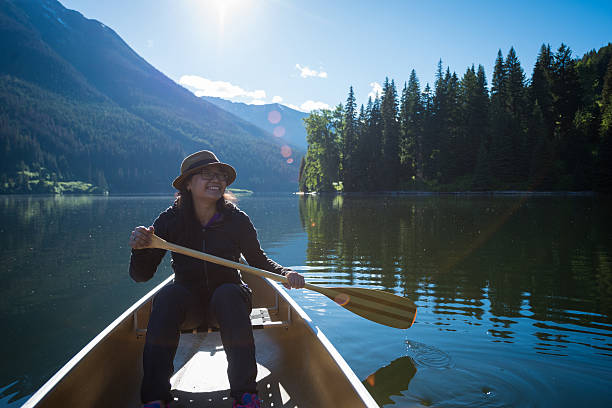 Woman in the great outdoors Female paddling a canoe on a pristine mountain lake at surise pemberton bc stock pictures, royalty-free photos & images