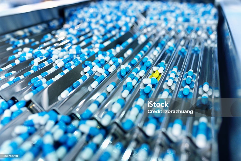 Capsule Production Line Side view of the capsule in production line. Medicine Stock Photo