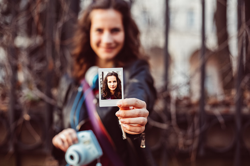 Smiling girl making instant photos with instant camera - copyspace