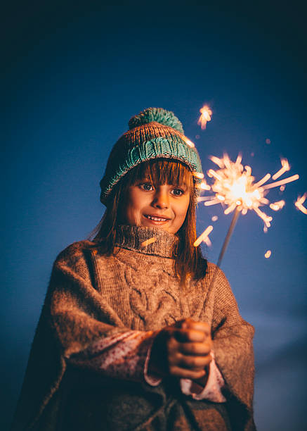 Little girl playing with a sparkler on November 5th for Bonfire Night.