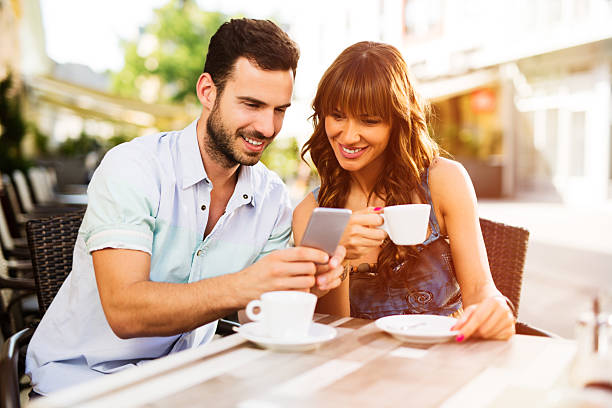istock Young affectionate heterosexual couple using mobile phone in cafe. 544802346