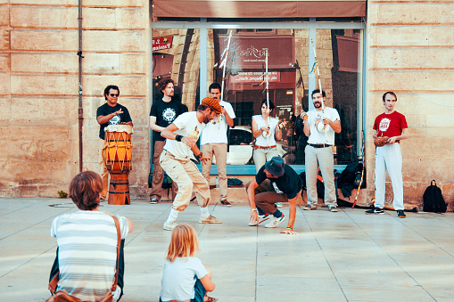 Bordeaux, France - August 24, 2015: People watch a homeless streetdancer doing breakdance and dance moves in the streets of Bordeaux to earn some money