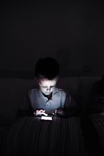 istock Little boy, sitting in a dark, playing with smartphone 544804090