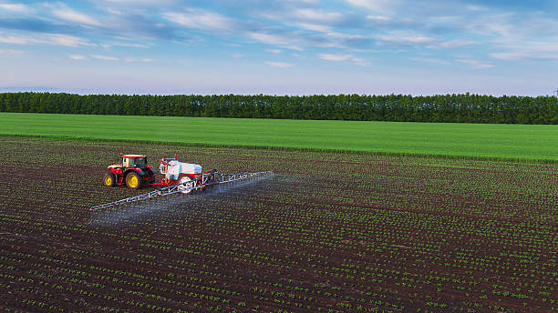 трактор напыления поле на spring - cultivated land farm land plowed field стоковые фото и изображения