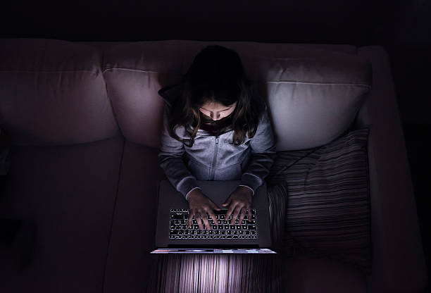 little girl, sitting in a dark, playing with laptop - child computer laptop little girls imagens e fotografias de stock