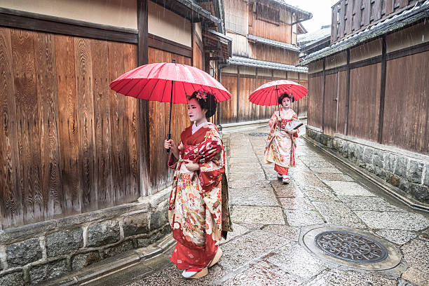 istock Two Japanese geishas in kimonos with red parasols 544806894