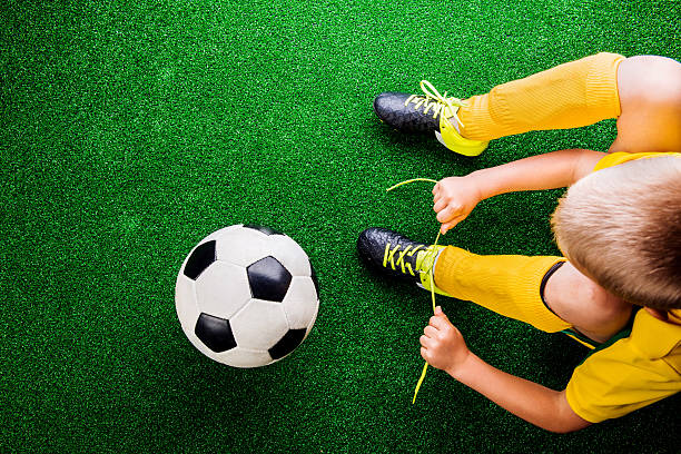 riconoscibile piccolo giocatore di calcio in erba verde, studi - soccer child indoors little boys foto e immagini stock