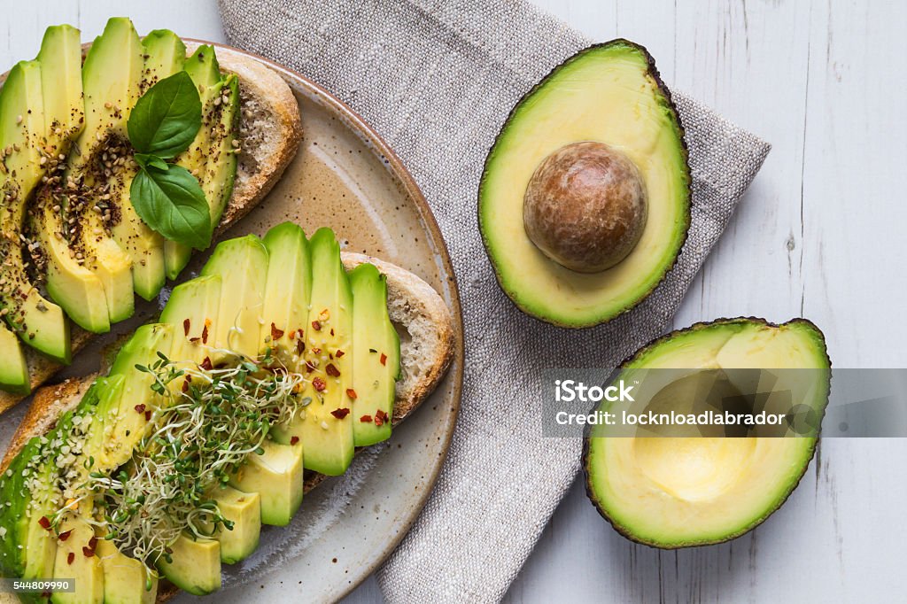 Toast with avocado and cress Toast with sliced avocado topping, basil leaf and seasoning. Avocado Stock Photo