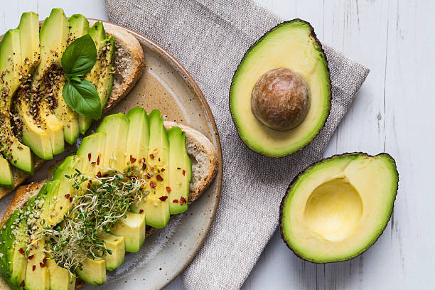 Toast with avocado and cress Toast with sliced avocado topping, basil leaf and seasoning. avocado stock pictures, royalty-free photos & images