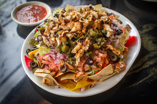Colorful Mexican nachos with chicken black olives melted cheese jalapenos and more