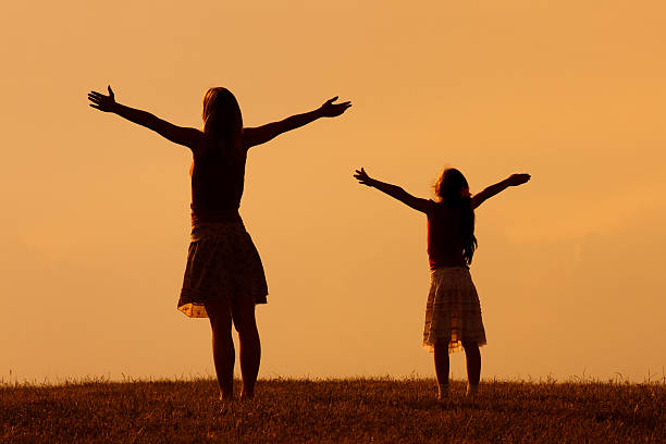 Mother and daughter enjoy in sunset together.