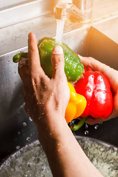 istock Male hands wash green paprika. 544815988