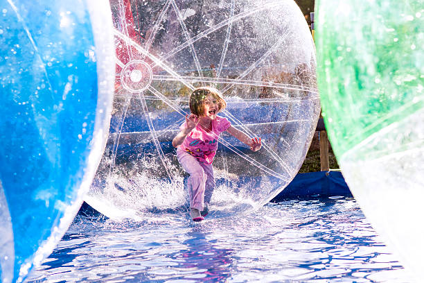 Girl in ball Young girl playing inside a floating water walking ball. zorbing stock pictures, royalty-free photos & images