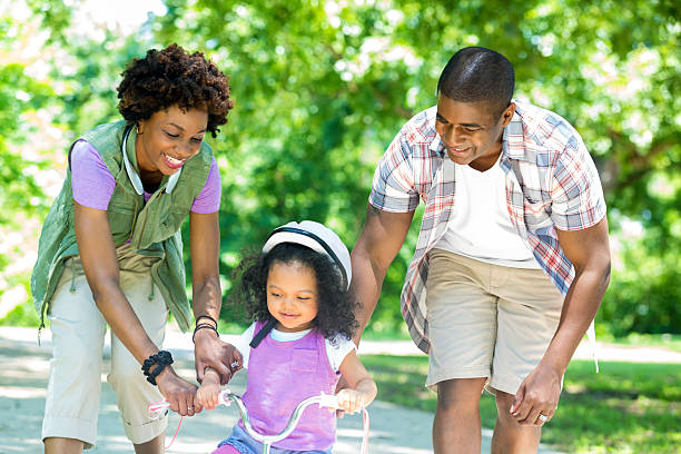istock Happy mom and dad teaching daughter to ride tricycle 544819342