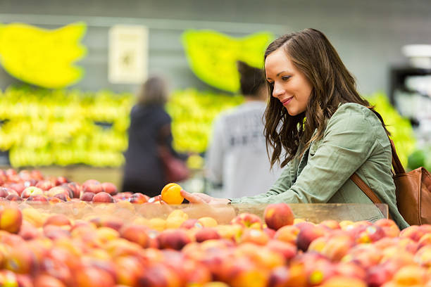 istock Beautiful woman shops for fruit in market 544820952