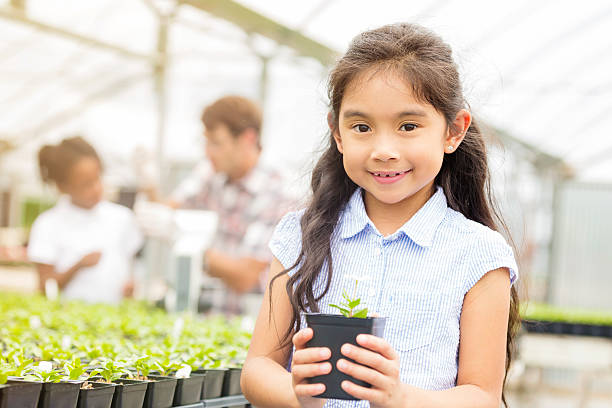 istock Cute elementary school girl holds plant in nursery 544957168