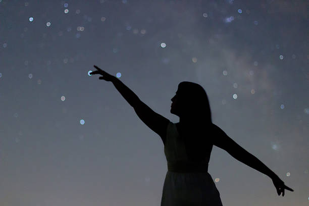 silhouette of a dancing woman pointing in night sky. - milky way galaxy space star imagens e fotografias de stock