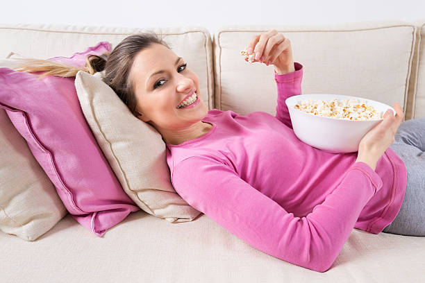 istock Beautiful young woman  lying on the sofa and eating popcorn. 544961898