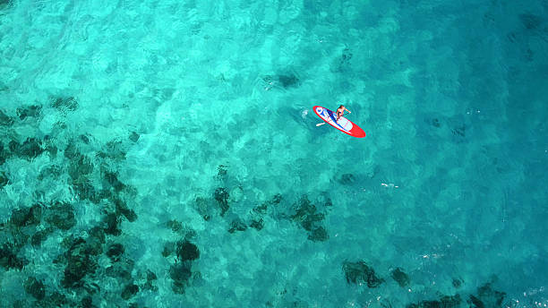 Aerial view of woman on paddleboard Aerial view of a woman on paddleboard in tropical water, Lovango Cay, United States Virgin Islands cay stock pictures, royalty-free photos & images